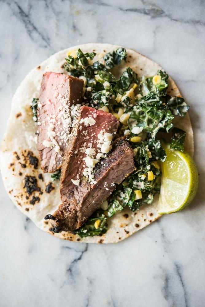 Rindfleisch Carne Asada auf Grünkohl und Krautsalat in einer Maistortilla auf einem Marmorbrett