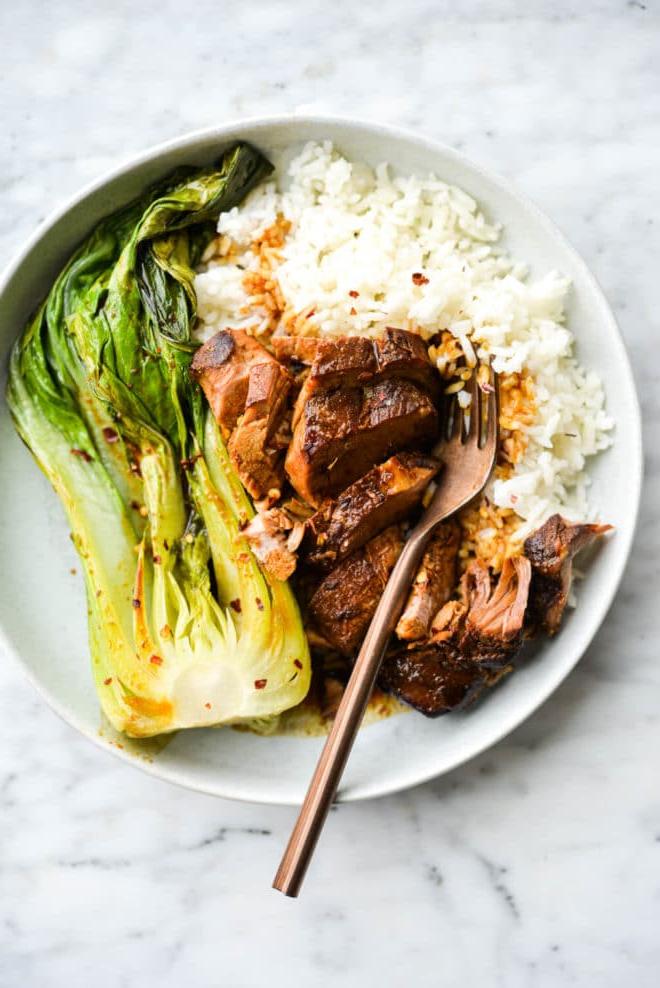 Eine flache Schüssel mit weißem Reis, Teriyaki-Schweinefilet und Pak Choi