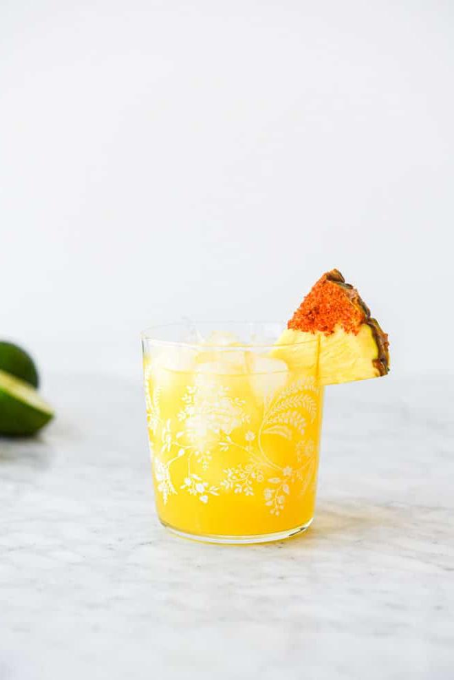 Ein Margarita-Glas mit einem Ananas Margarita auf Eis, garniert mit einem in Chili-Salz getauchten Ananas-Keil.