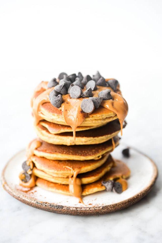 Ein Stapel Protein-Pancakes, garniert mit Erdnussbutter und Schokoladenstückchen.
