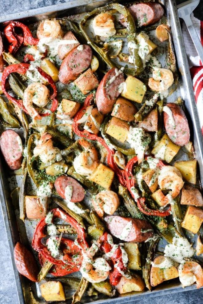 Ofenblech mit Wurst, Garnelen, Kartoffeln, Spargel und roten Paprika, übergossen mit einer cremigen Soße – Draufsicht
