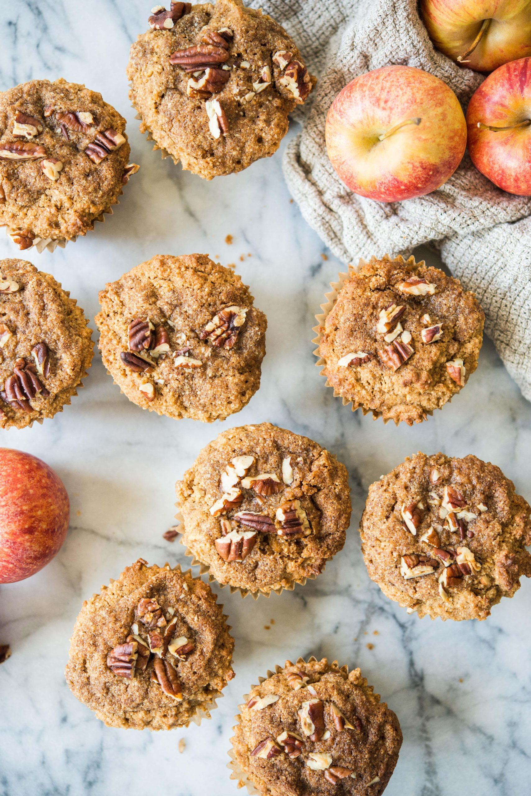 paleo apple cinnamon muffins on a marble board surrounded by apples