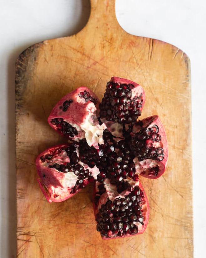 Ein segmentierter Granatapfel auf einem Holzschneidebrett
