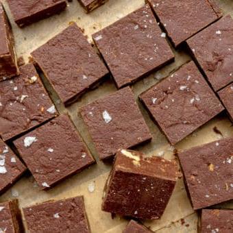 Hausgemachtes Schokoladen-Walnuss-Fudge 5 Kleine Quadrate aus Schokoladenfudge auf einem braunen Stück Backpapier.