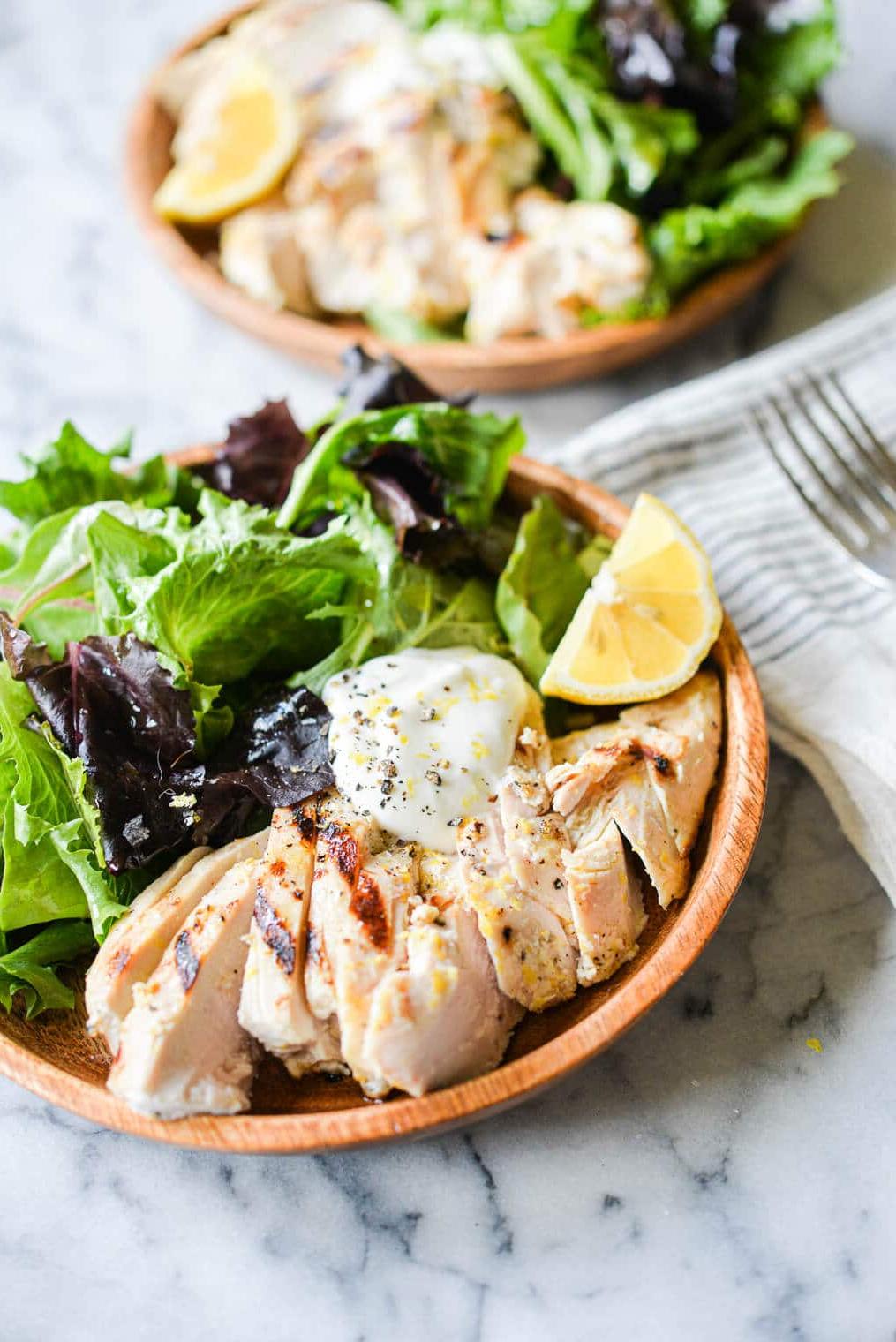Geschnittenes Zitronen-Pfeffer-Joghurt-Hähnchen vom Grill, serviert in einer Schale auf gemischtem Salat
