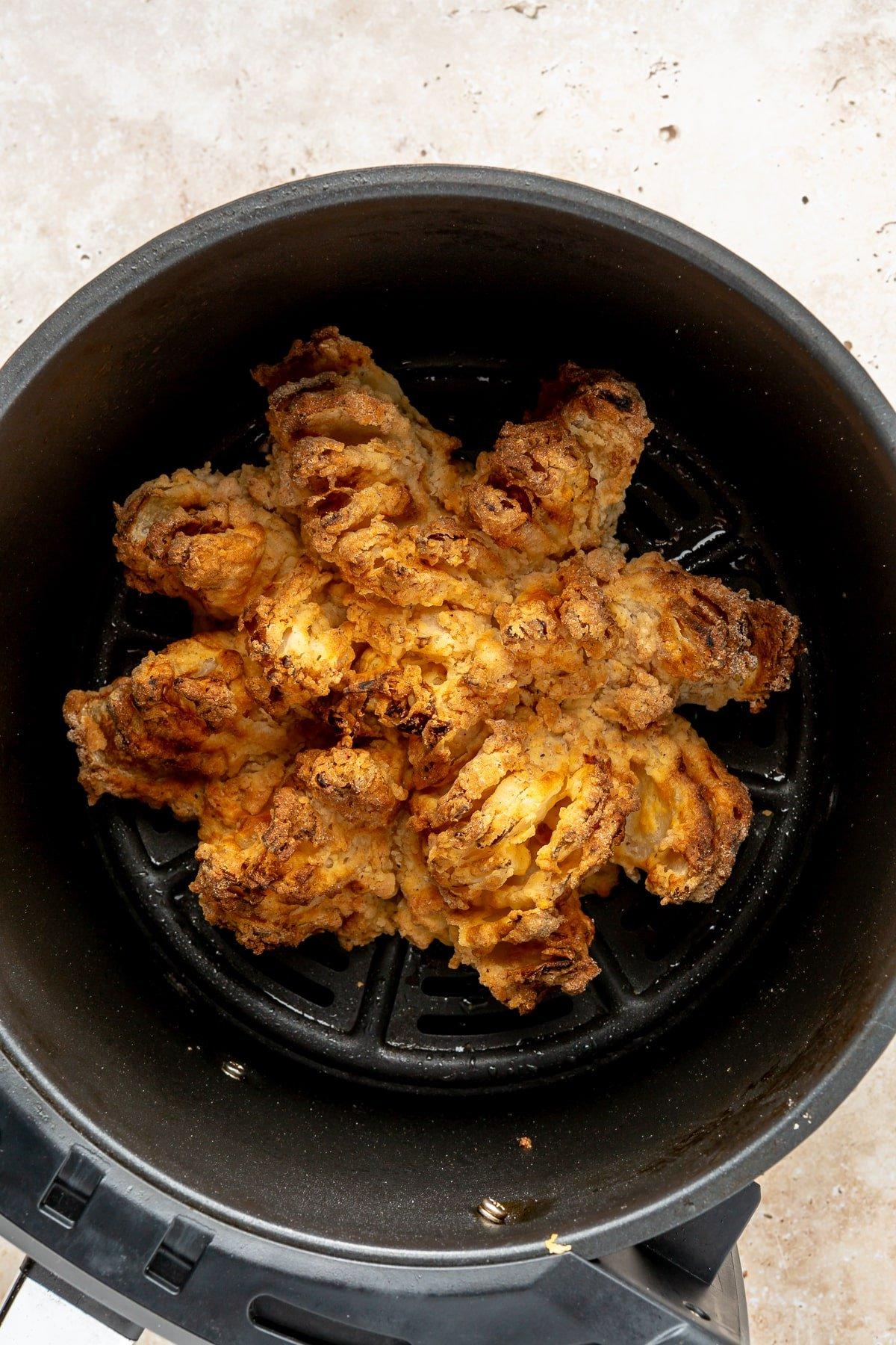 Schritt 8: Die frisch zubereitete Blühende Zwiebel wird appetitlich auf einem Teller angerichtet, daneben eine Schale mit der cremigen Dip-Soße, bereit zum Genießen.