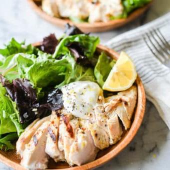 Geschnittenes Zitronen-Pfeffer-Joghurt-Hähnchen vom Grill, serviert in einer Schale auf gemischtem Salat