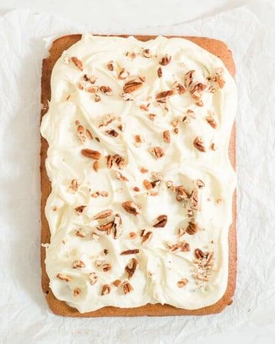 Glasierter Kuchen mit Pekannüssen Ein glasierter Gewürzkuchen mit Pekannüssen bestreut auf einem Stück zerknittertem Backpapier