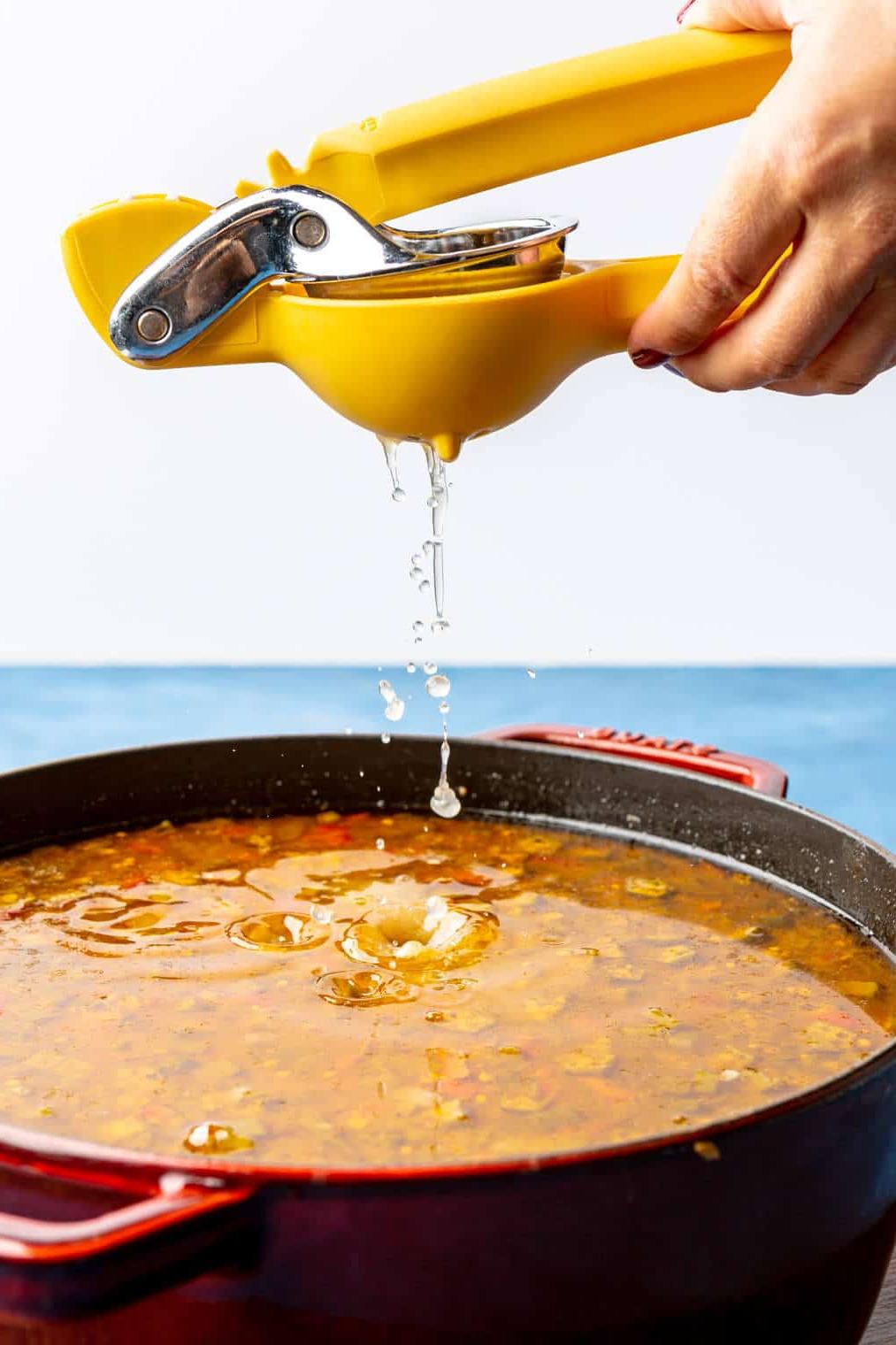 Zitronensaft wird über einen Topf Gumbo gepresst.