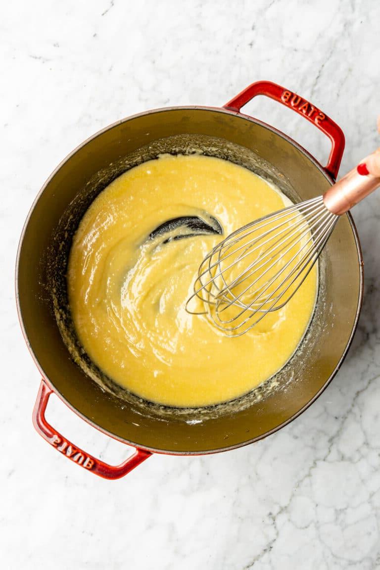 Schneebesen mit Butter und Mehl in einem großen holländischen Ofen, der eine Roux bildet.