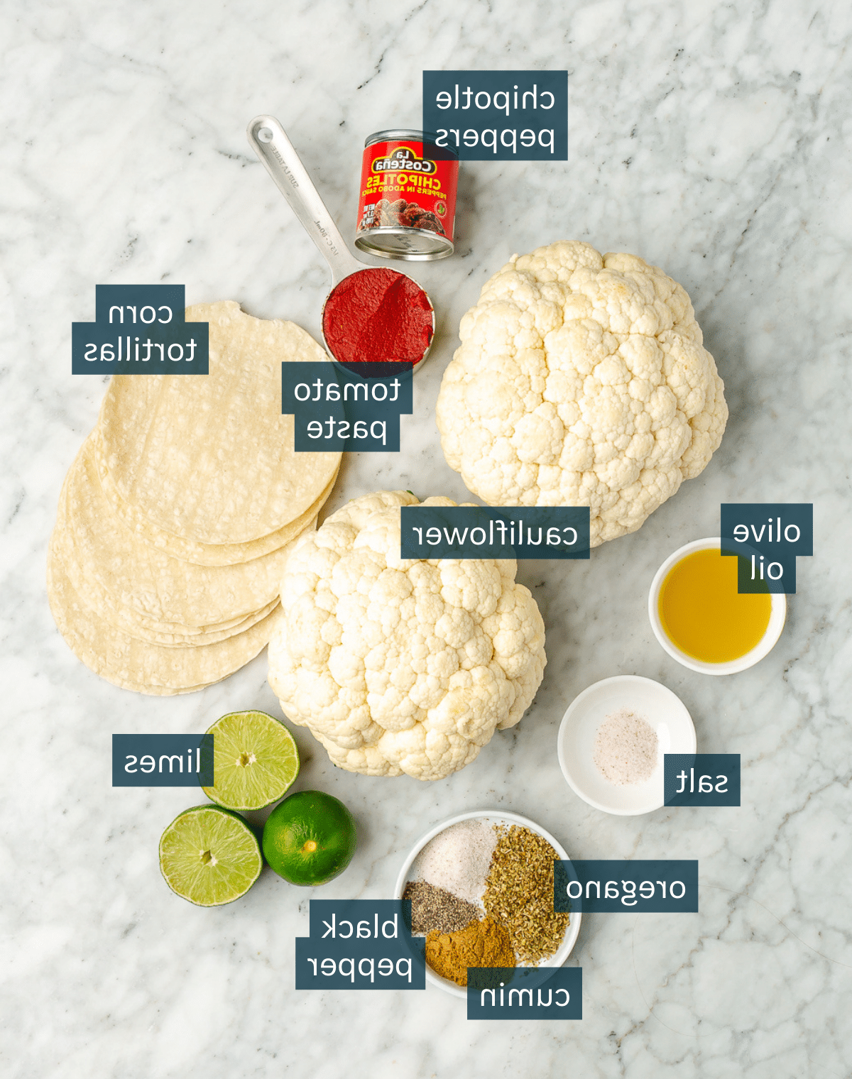 Alle Zutaten für Blumenkohl-Tinga-Tacos auf einer Marmoroberfläche.