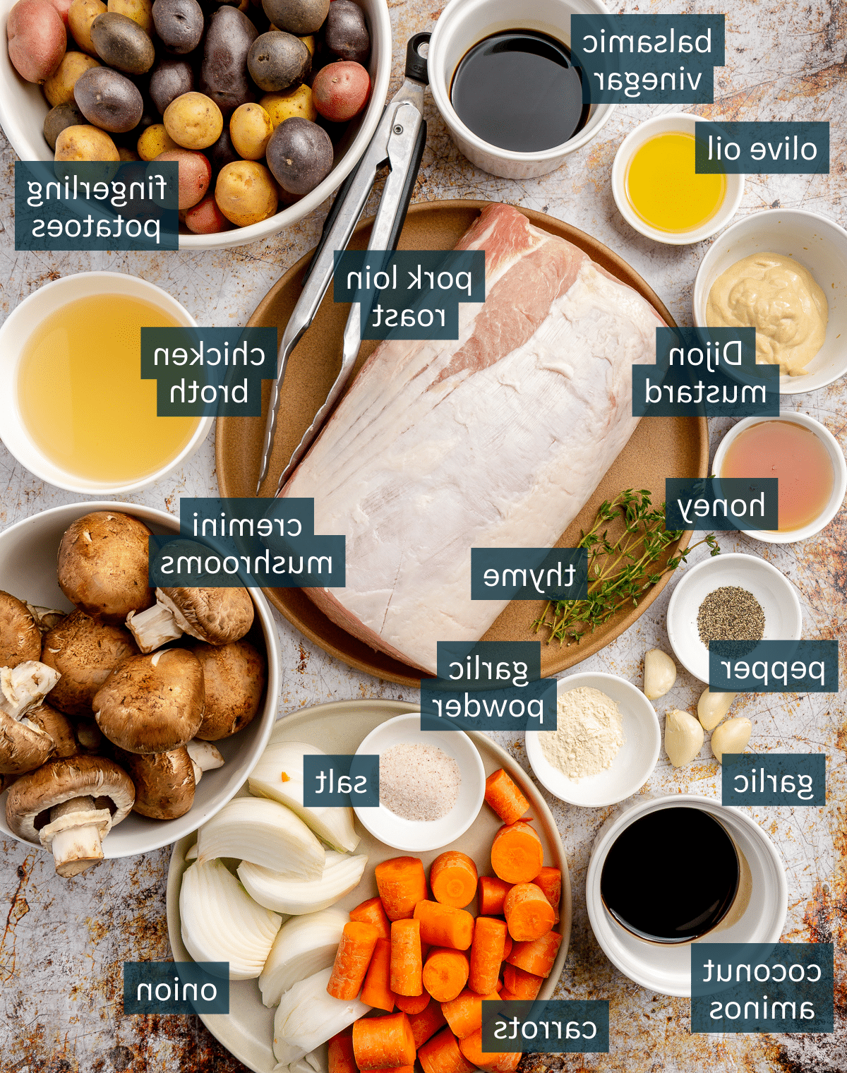 Zutaten für Balsamico-Schweinebraten liegen in verschiedenen Schalen auf einem leicht verrosteten Backblech.