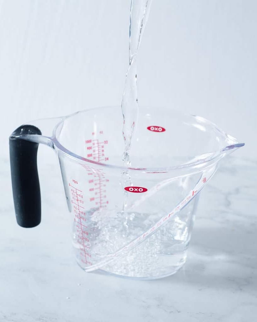 Eine Person gießt Wasser in einen Messbecher
