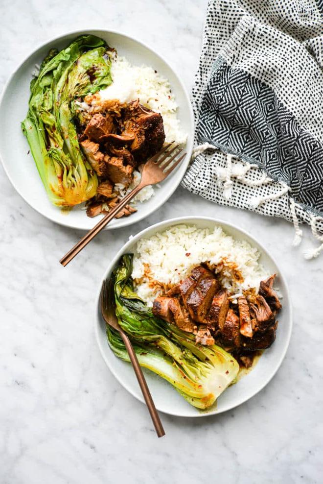 Zwei flache Schüsseln mit weißem Reis, Teriyaki-Schweinefilet und Pak Choi