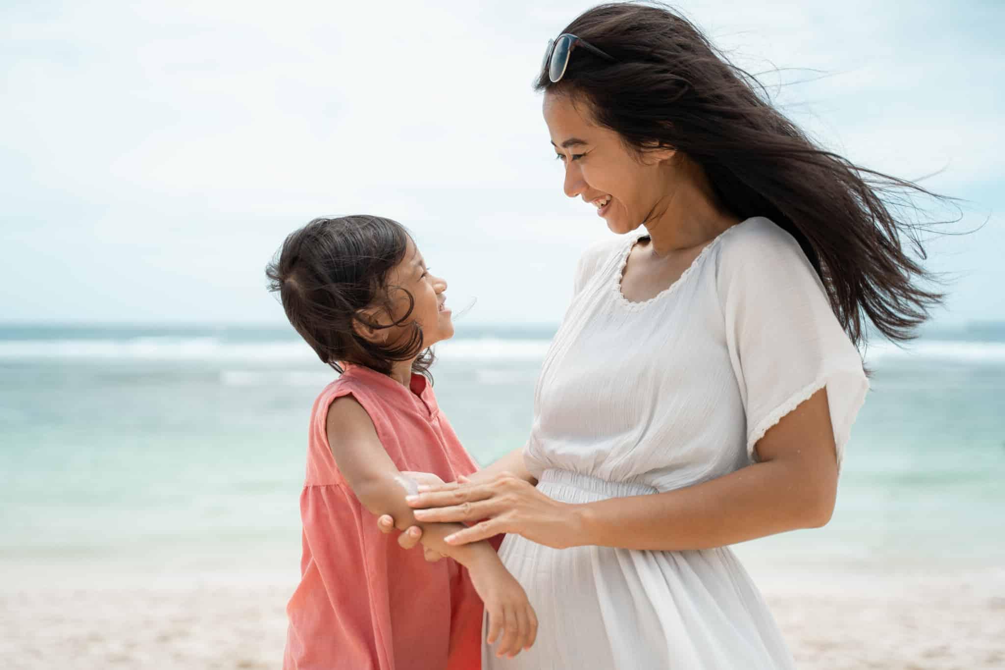 Eine Mutter cremt ihrer Tochter am Strand Sonnencreme ein