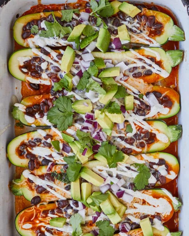 Enchilada-gefüllte Zucchiniboote, garniert mit Sauerrahm, Avocado und Koriander