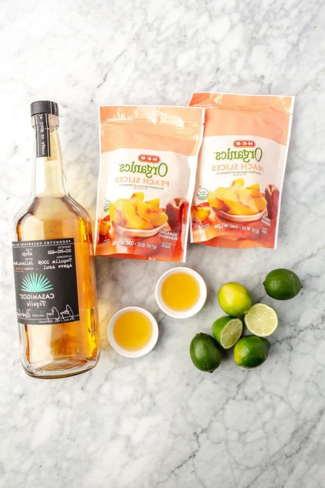 Zutaten für gefrorene Pfirsich Margarita auf einer Marmoroberfläche.