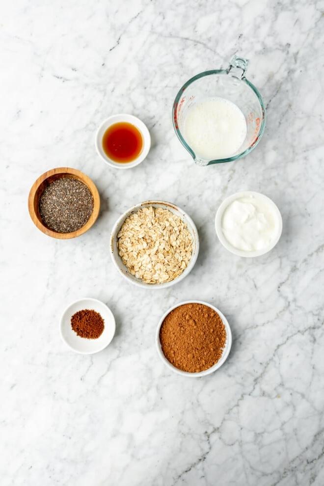 Zutaten für Tiramisu Overnight Oats auf einer grau-weißen Marmoroberfläche.