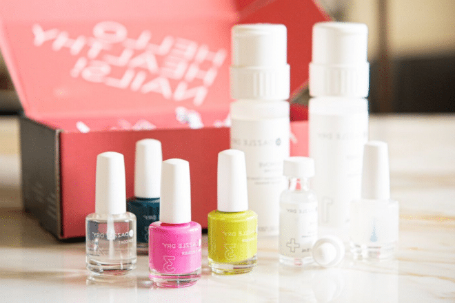 Dazzle Dry Nagelset mit drei Nagellacken, einem Überlack und einem Entferner vor einer leuchtend rosafarbenen Box