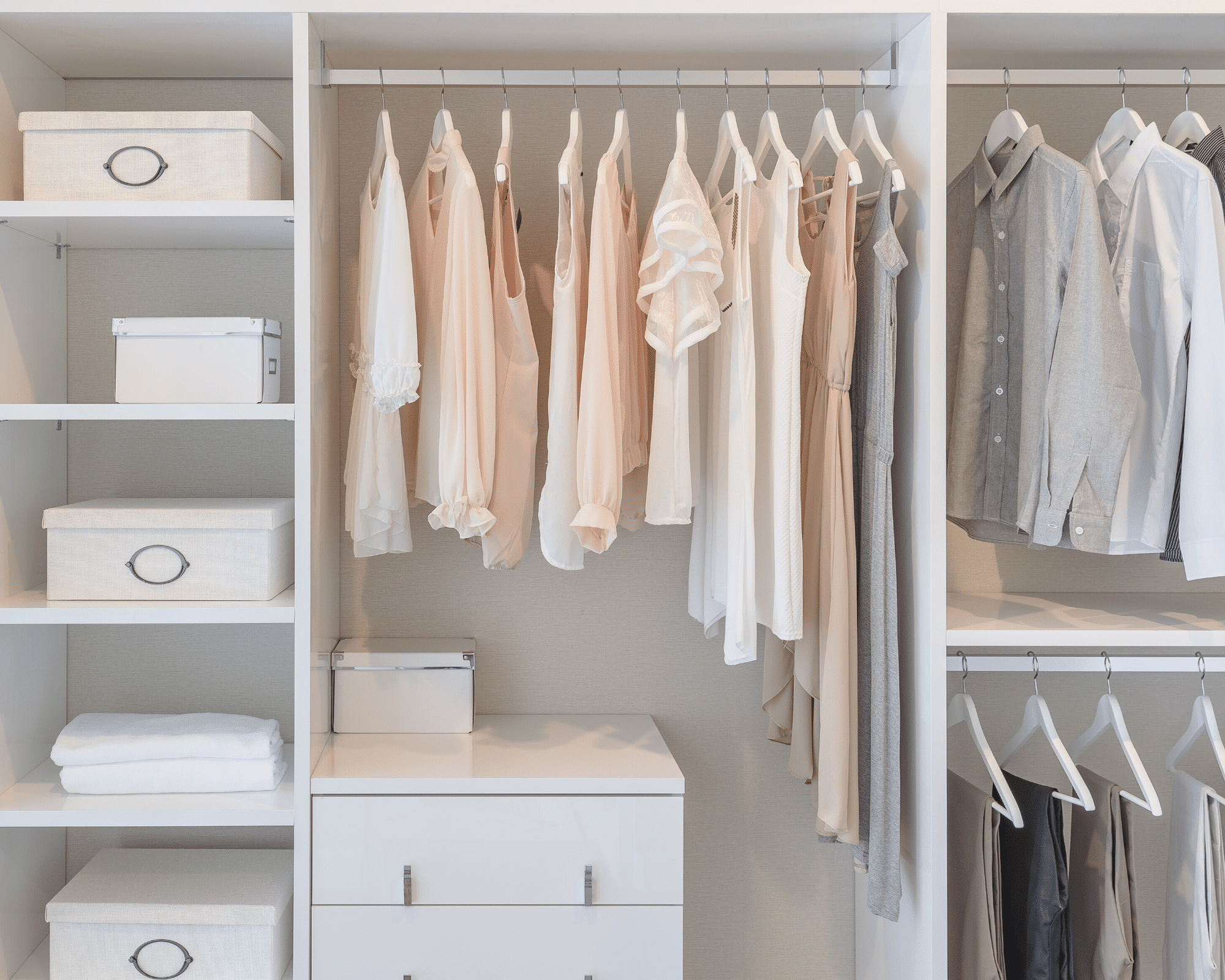 Organisierter Kleiderschrank mit weißen und rosa Hemden, einer Kommode und weißen Boxen