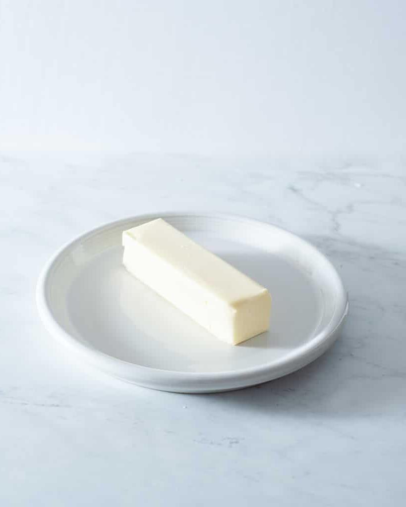 Ein Stück Butter auf einem kleinen weißen Teller