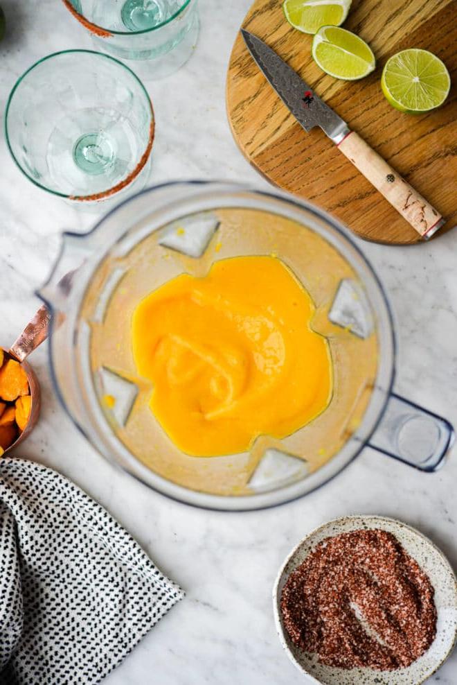 Eine Top-Down-Aufnahme einer Kanne Frozen Mango Margaritas umgeben von den anderen benötigten Zutaten