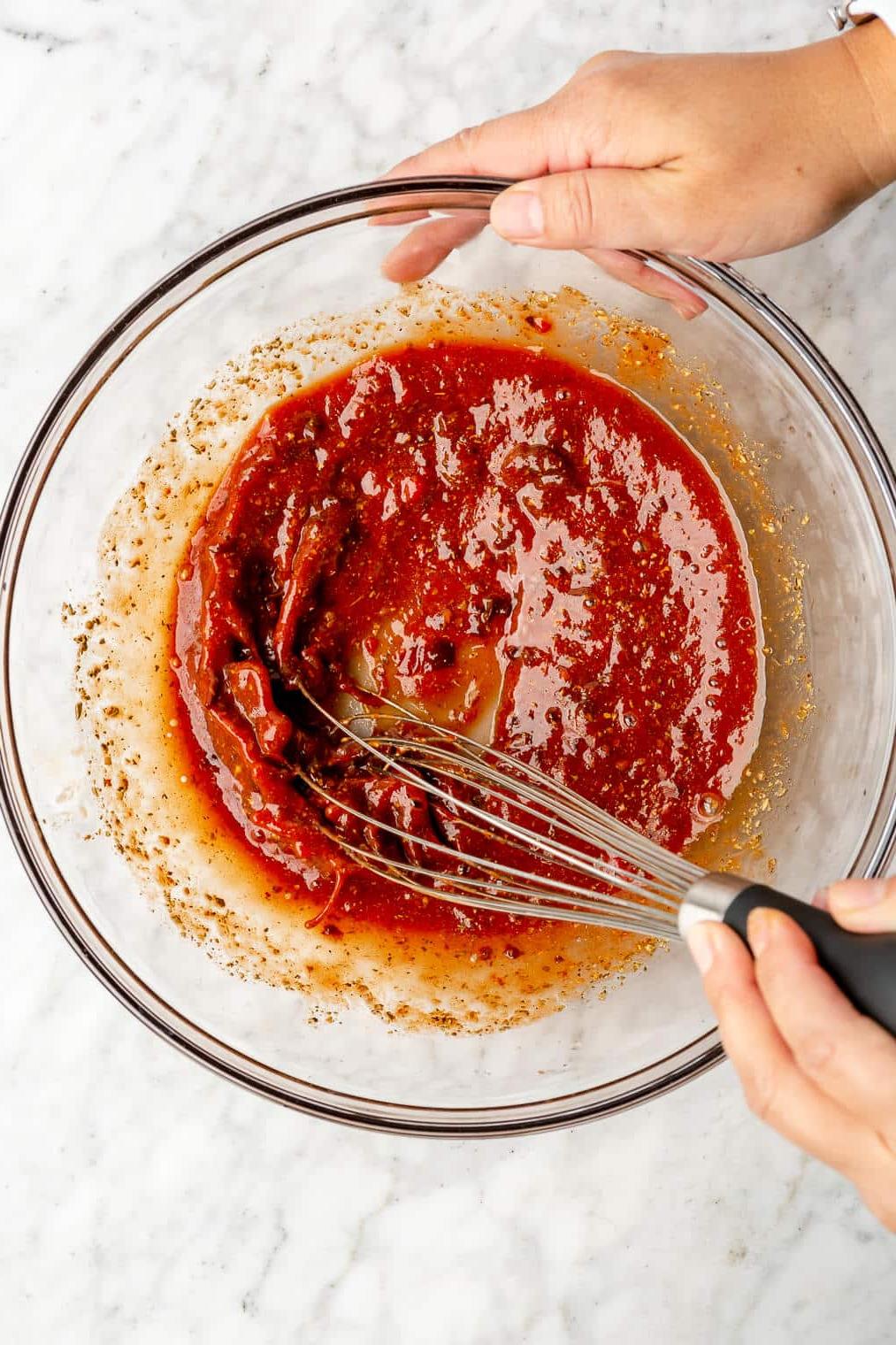 Eine Person verrührt eine leuchtend rote Tinga-Sauce für Blumenkohl-Tinga-Tacos.