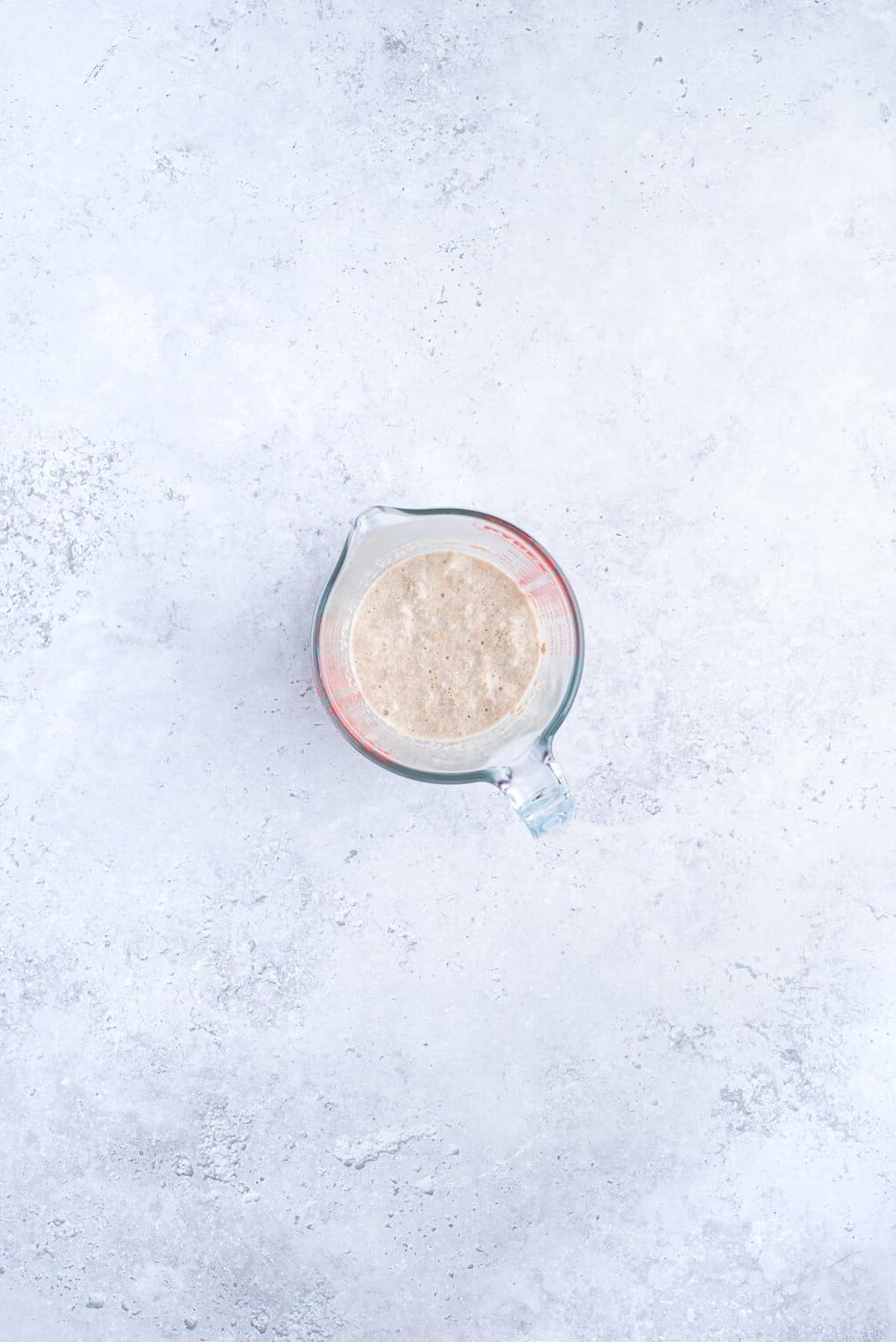 Ein Messbecher mit Milch, Hefe und Zucker