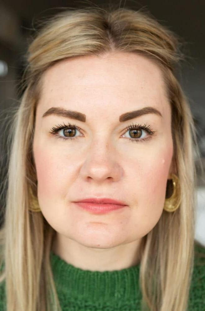 Nahaufnahme von Lauren in einem kellygrünen Pullover, die nicht lächelt und Honest Mascara trägt.