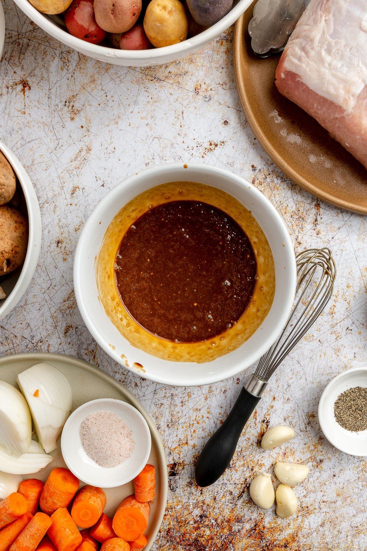 Die dunkelbraune Sauce und das Pulver wurden zu einer goldbraunen Mischung verquirlt. Ein jetzt schmutziger schwarzer Schneebesen liegt daneben.