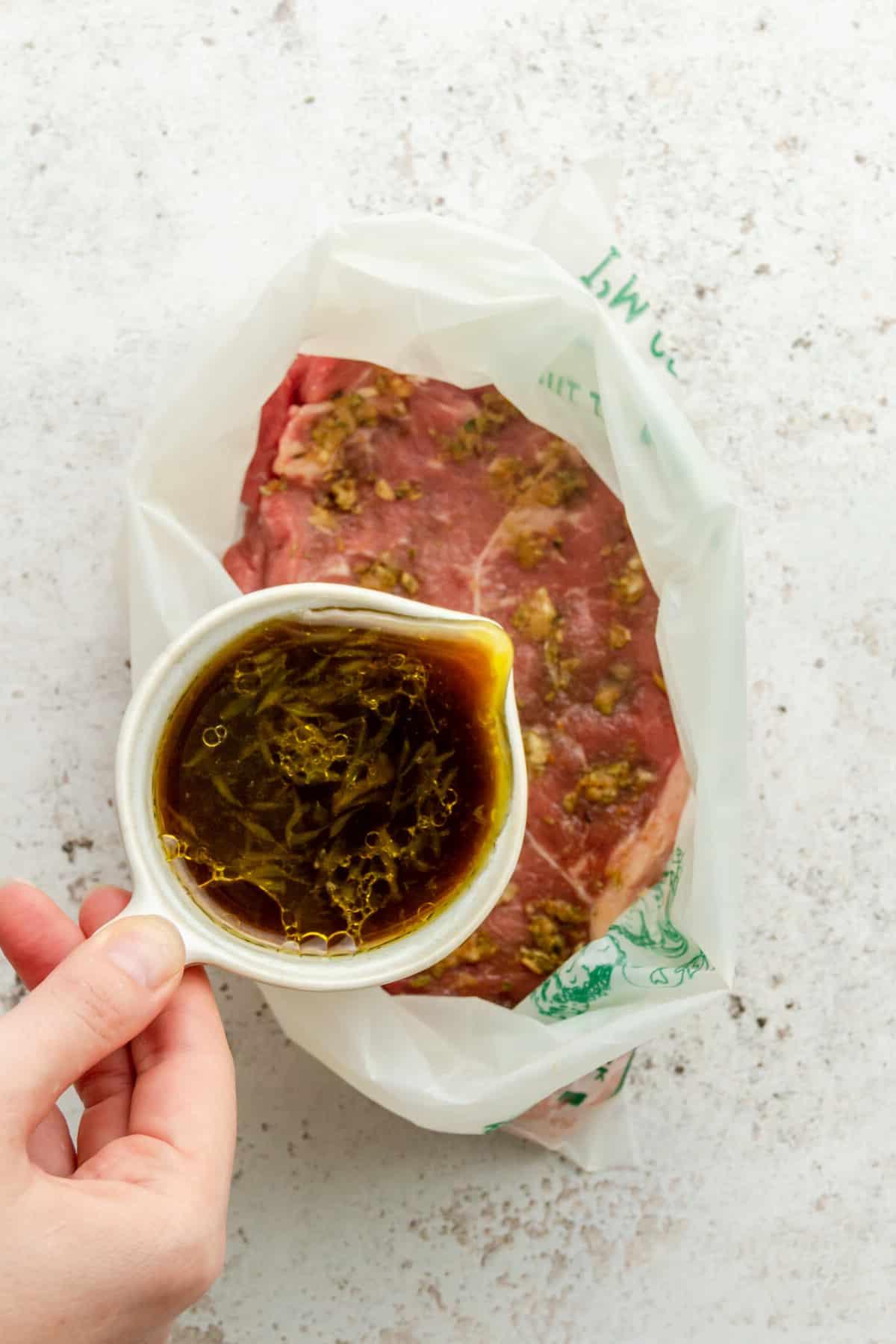 Eine Limettenmarinade wird über adobo-gewürztes Steak in einem Ziploc-Beutel auf einer hellgrauen Oberfläche gegossen.
