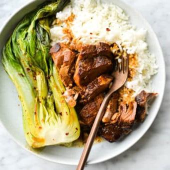Eine flache Schüssel mit weißem Reis, Teriyaki-Schweinefilet und Pak Choi