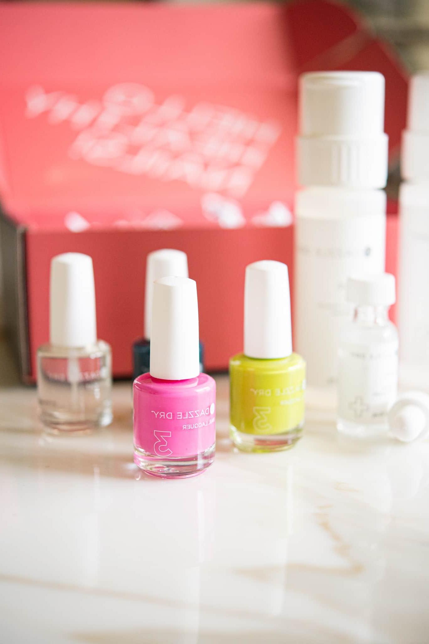 Ein Set aus pinkem Nagellack mit gelbem und klarem Lack dahinter, kunstvoll positioniert vor einer passenden pinken Box – das Dazzle Dry Nagelsystem in seiner ganzen Pracht.