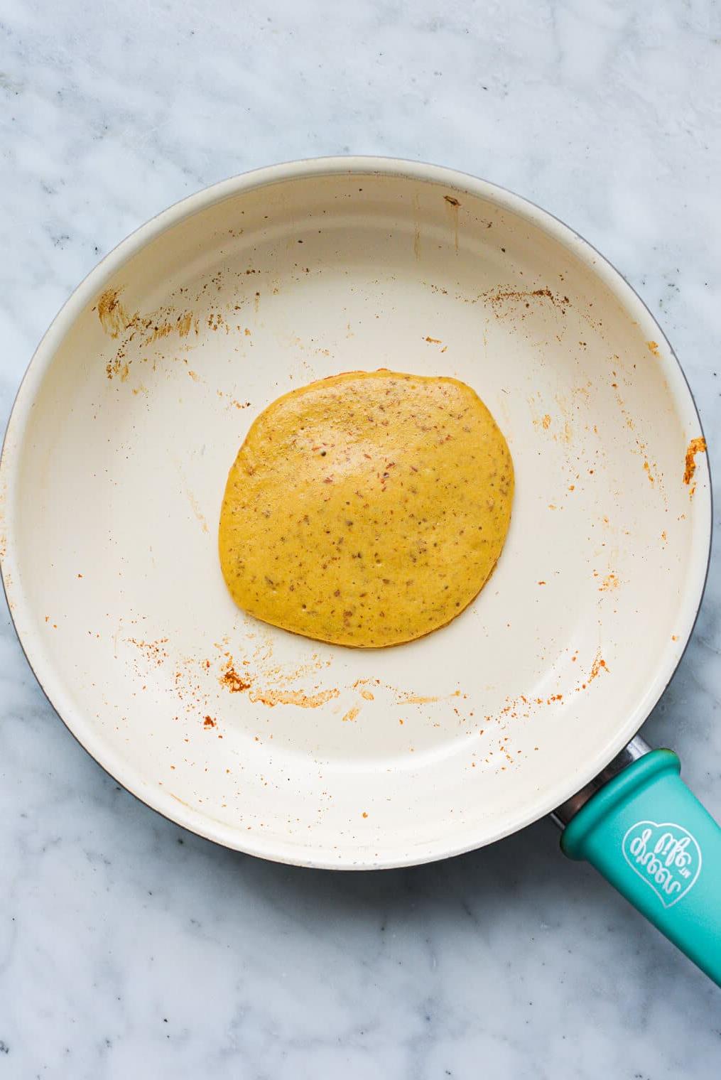 Ein Protein-Pancake kocht in einer Antihaftpfanne.