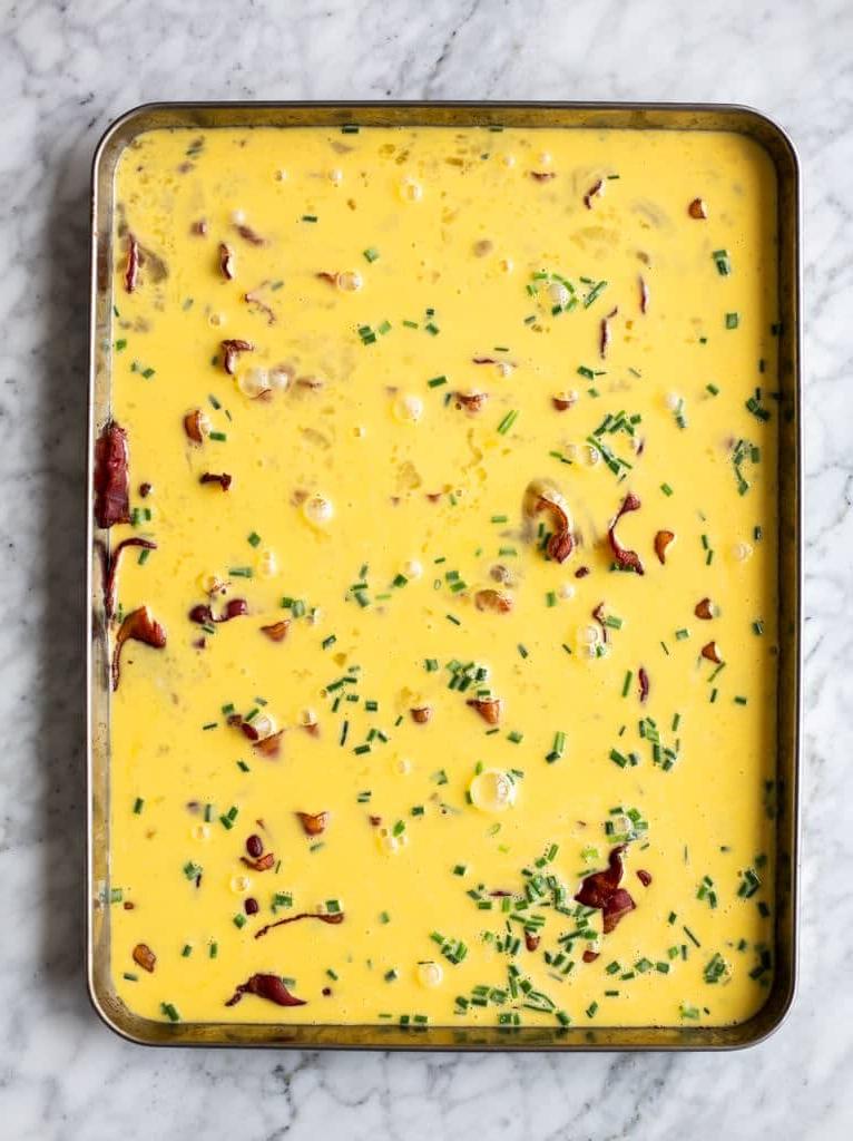 Backblech mit Speck, verquirlten Eiern und Schnittlauch.