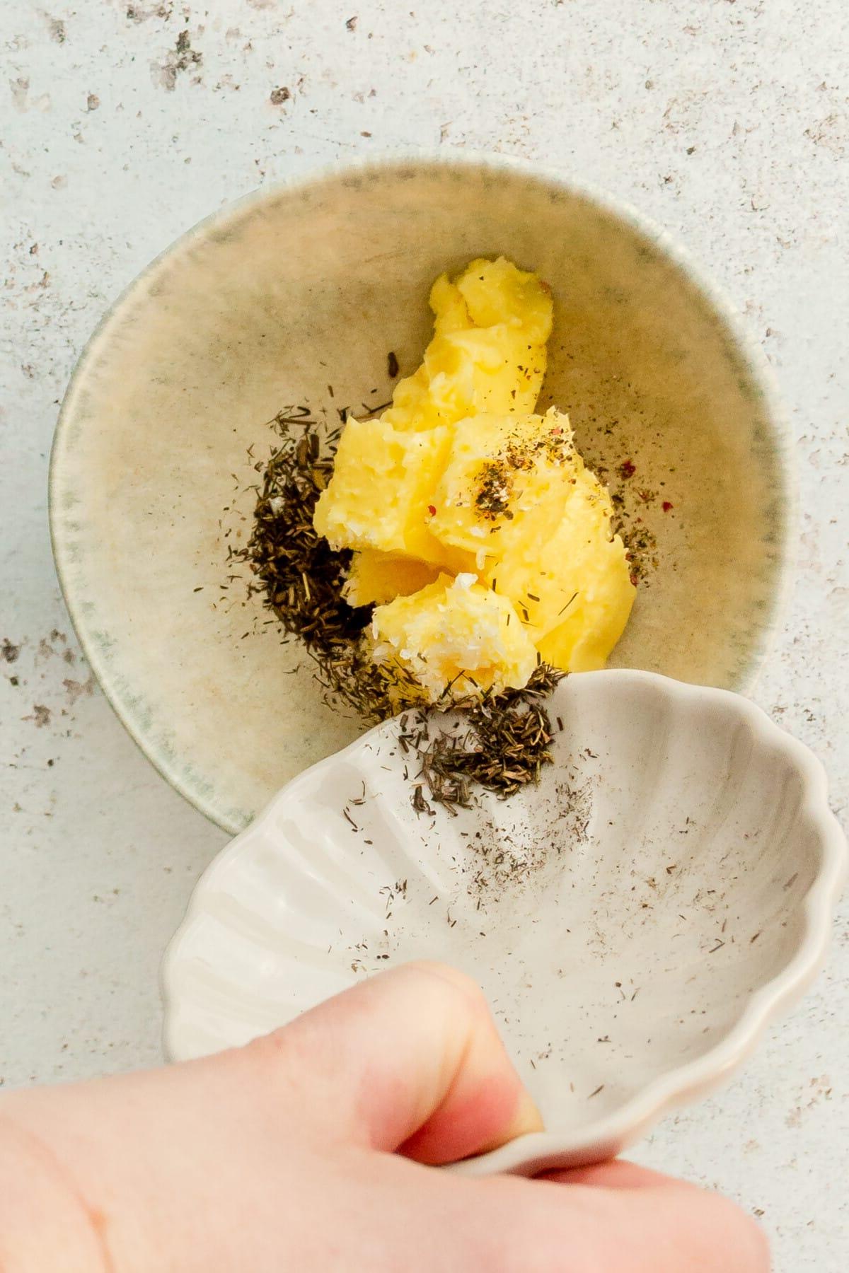 **Kirsch-Balsamico-Ofenhähnchen** 5 Getrockneter Thymian wird in Butter in einer kleinen blauen Keramikschale auf hellem Untergrund gemischt.
