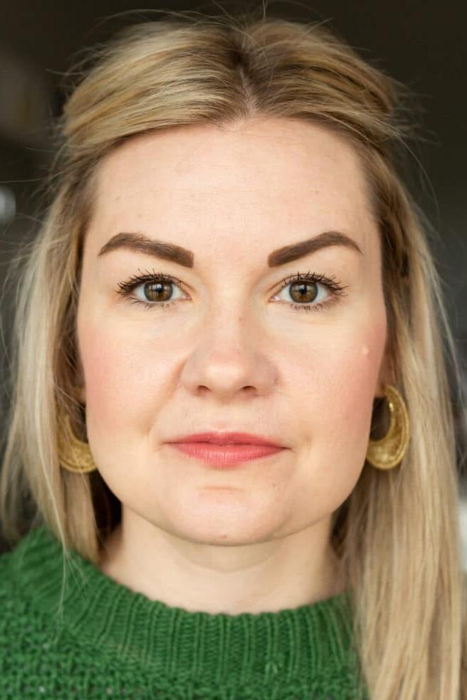 Nahaufnahme von Lauren in einem kellygrünen Pullover, die nicht lächelt und Cover Girl Mascara trägt.