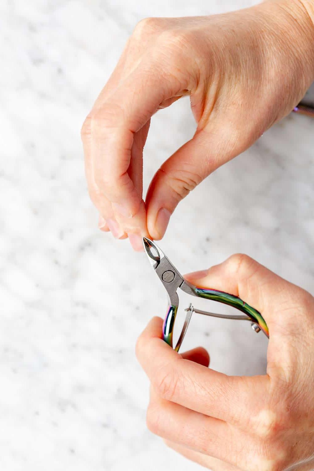 Hände schneiden Nagelhaut mit Nagelhautschneider.