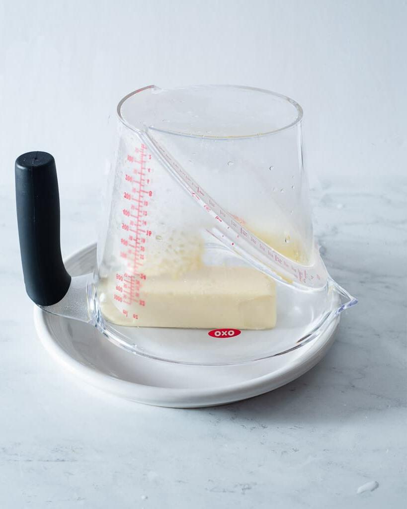 Ein dampfender Messbecher umgedreht über einem Stück Butter