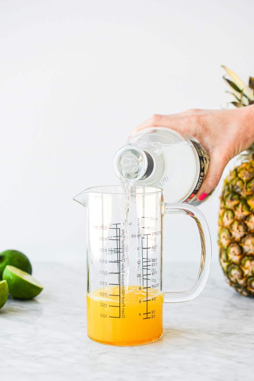 Eine Person gießt Tequila in einen großen Messbecher aus Glas.
