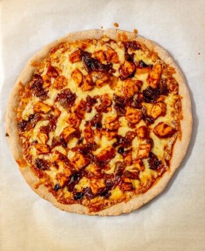 Eine gebackene BBQ Hähnchen Pizza vor dem Garnieren.