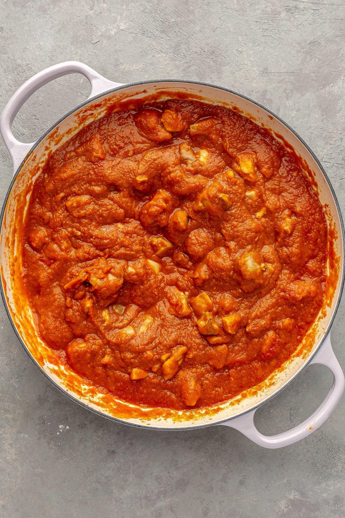 Einfaches Kürbiscurry-Rezept 6 Alle Zutaten wurden zu einer roten, sämigen Mischung vermischt. Alles befindet sich in einem weißen emaillierten Topf.