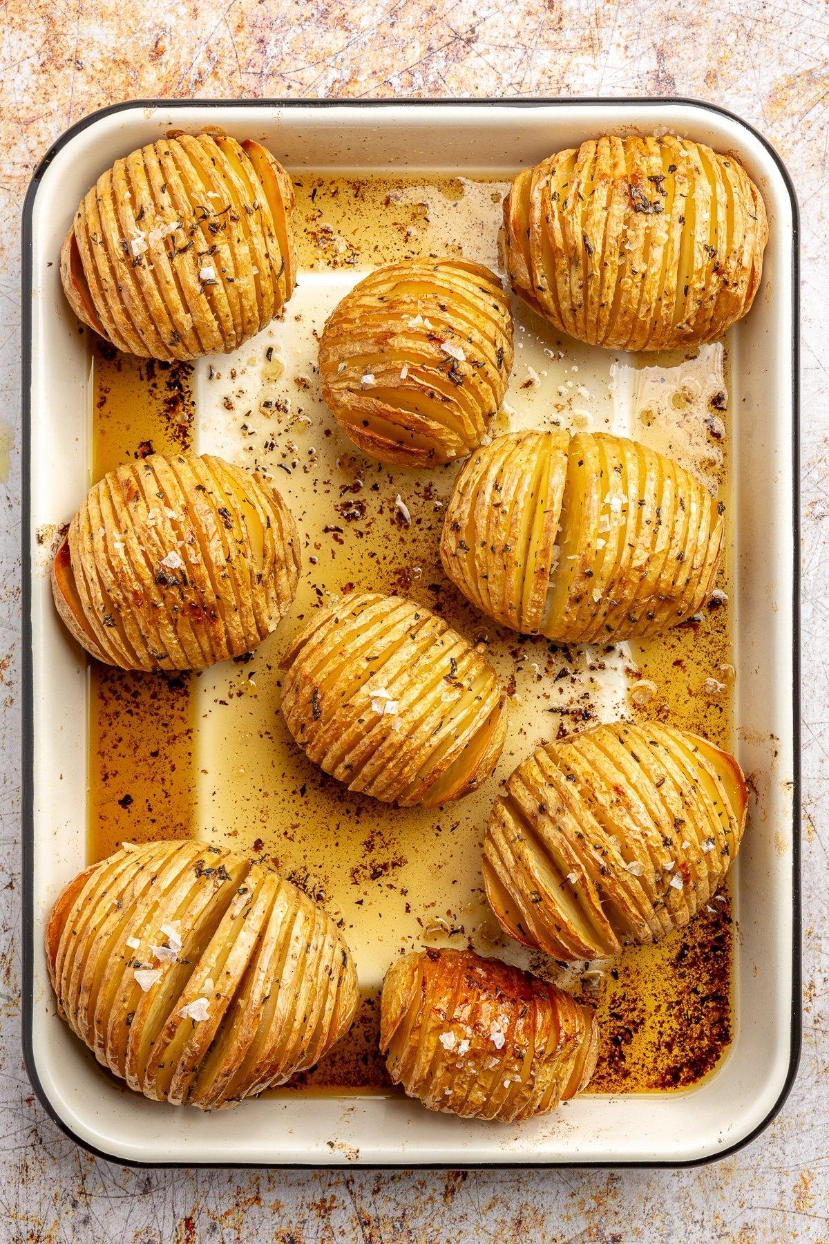 Fertig gebackene, goldbraune Kartoffeln liegen auf einem Backblech. Grobes Salz ist darüber gestreut.