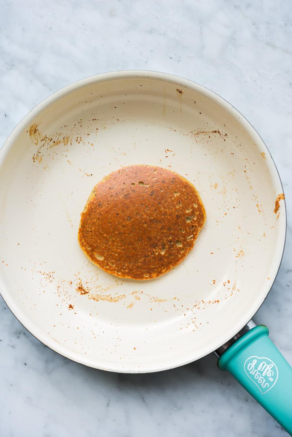 Ein Protein-Pancake kocht in einer Antihaftpfanne.