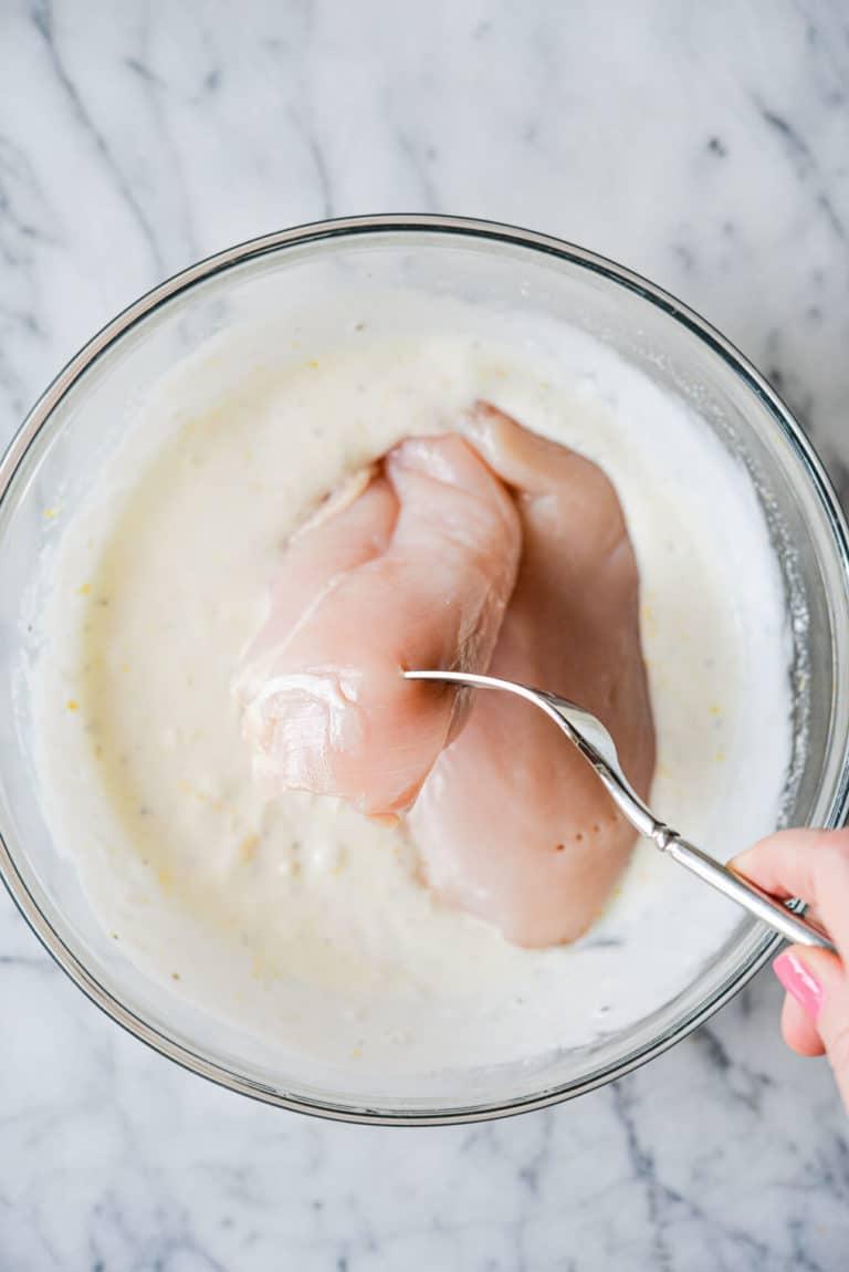 Rohe Hähnchenbrüste werden in Zitronen-Joghurt-Marinade getaucht