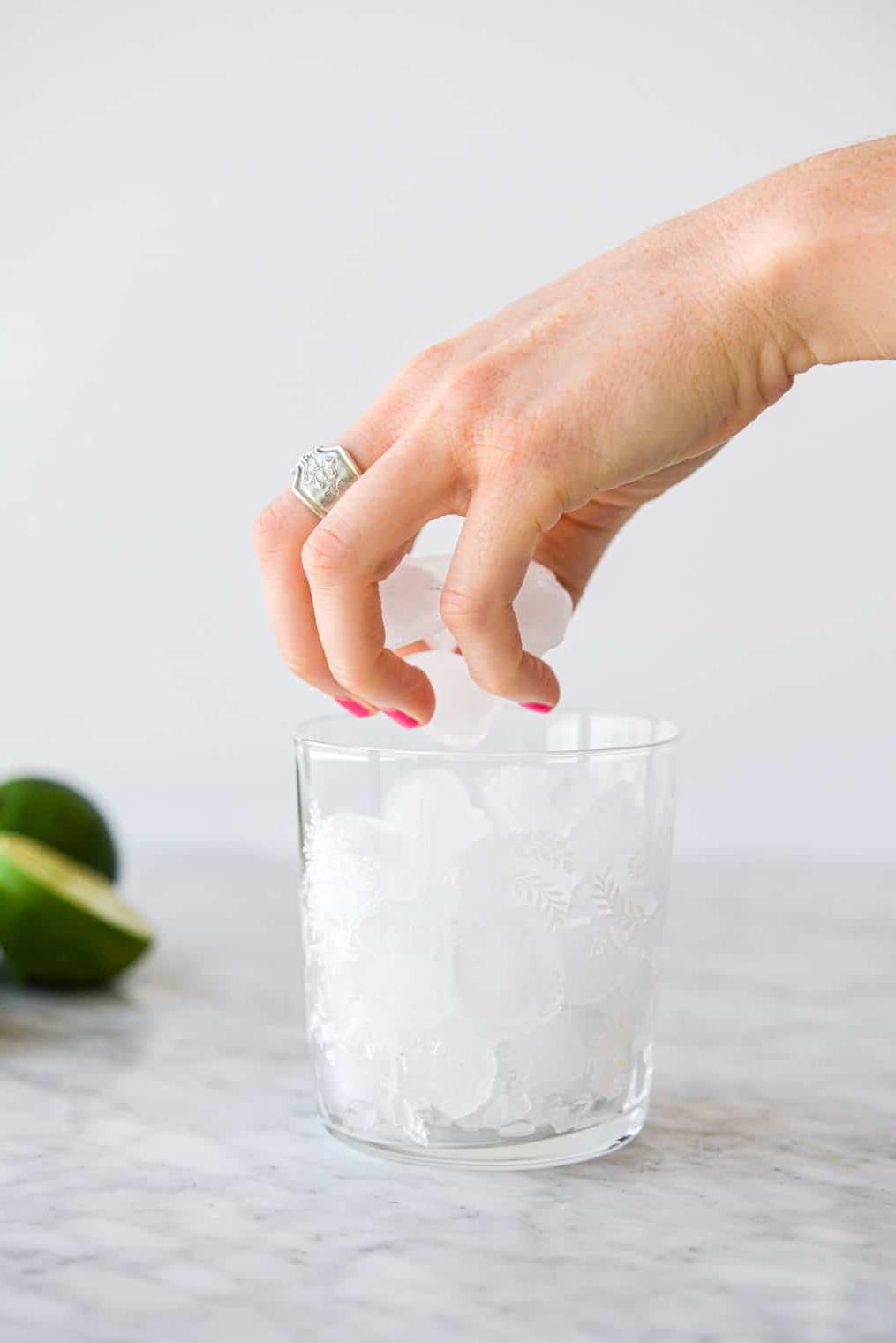 Eine Person legt Eiswürfel in ein kleines Margarita-Glas.