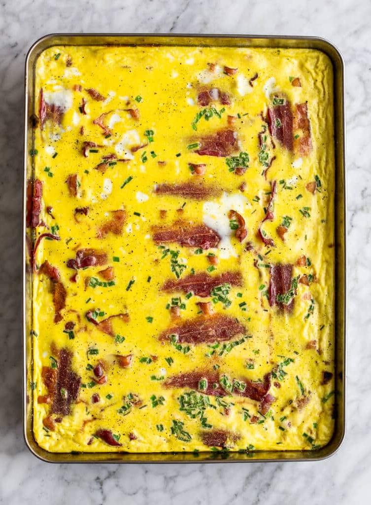 Backblech mit Speck, gebackenen Eiern und Schnittlauch.