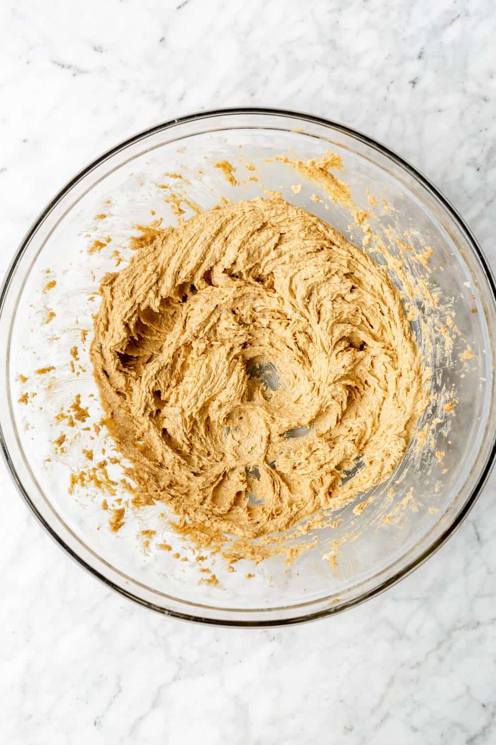 Draufsicht auf Butter und Zucker, die in einer Glasschüssel cremig geschlagen werden.