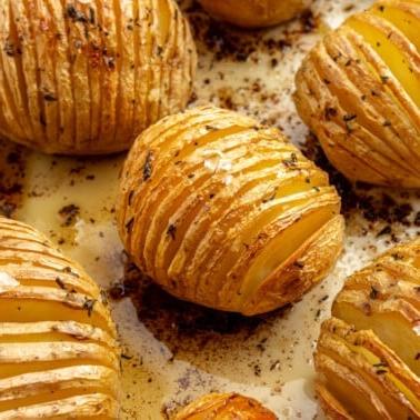 Fertig gebackene, goldbraune Kartoffeln liegen auf einem Backblech. Grobes Salz ist darüber gestreut.