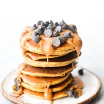 Ein Stapel Protein-Pancakes, garniert mit Erdnussbutter und Schokoladenstückchen.